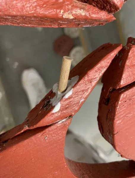 Cheville en bois neuve dans l’angle d’un cadre de volet rouge