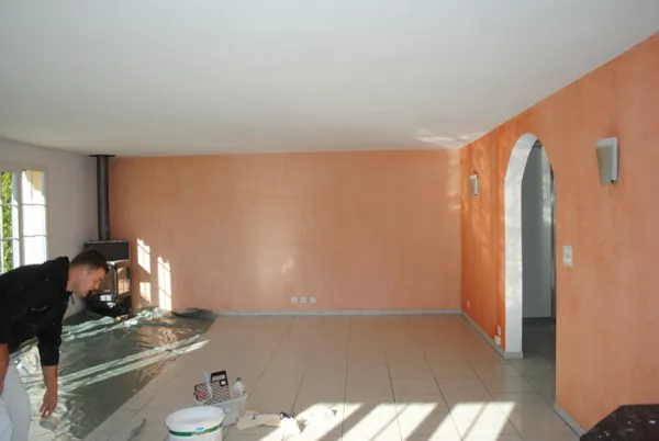 Mur de séjour repeint couleur corail, sol clair au premier plan