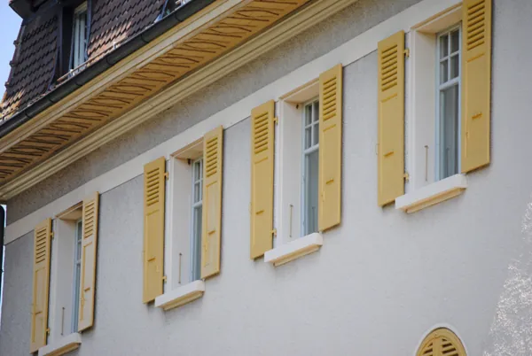 Maison aux murs blancs et aux volets jaune vif