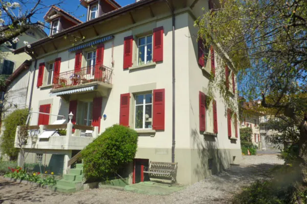 Chalet à façade claire, volets repeints en rouge