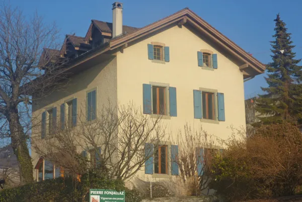 Ancienne ferme au crépi jaune, volets verts restaurés